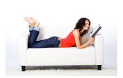 Woman laying on a couch reading