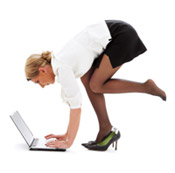 A woman crouching in front of a laptop computer